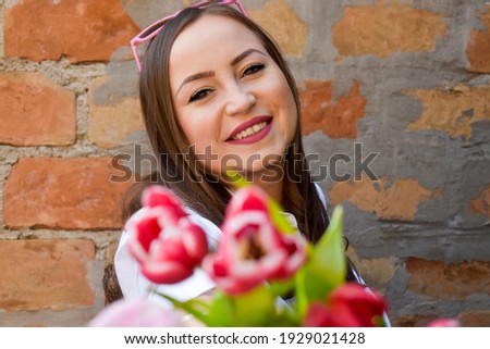 Woman in front of a brick wall holding tulips 