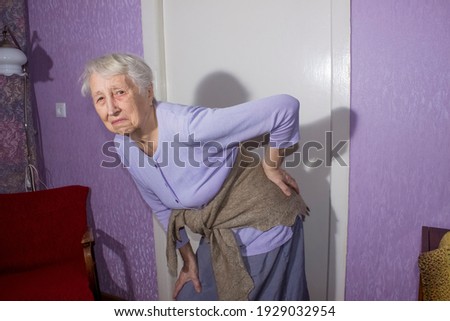 Elderly senior 75s woman with painful feelings in lumbar, massaging low back to reduce ache, suffer from backache discomfort. Diseases of older people, sciatic nerve injury and radiculitis concept Royalty-Free Stock Photo #1929032954