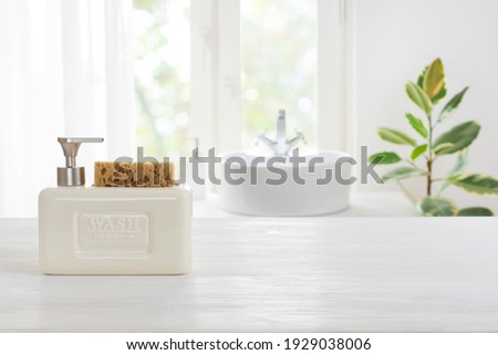Hygienic soap dispenser on table against defocused bathroom sink background