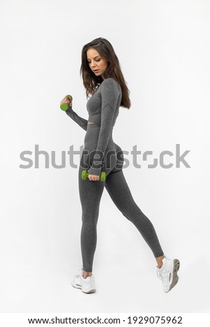 Fitness woman in sportswear doing exercises with dumbbells on white background.
