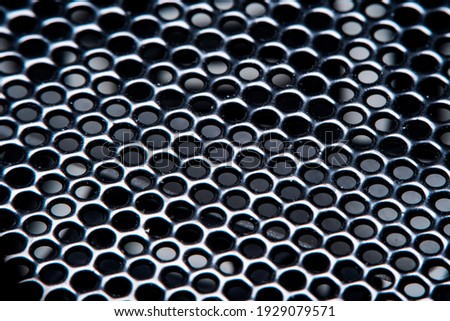 Background with dusty metal grill, black metal mesh with round holes in soft focus under high magnification