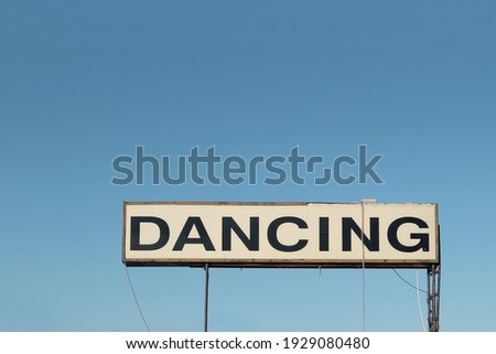 an old dancing sign over a blue sky