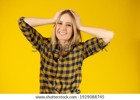 Attractive thoughtful young woman standing isolated over yellow background