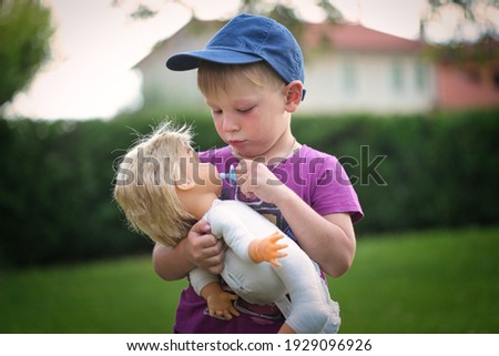 little boy playing with a doll in nature 2021 Royalty-Free Stock Photo #1929096926