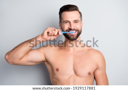 Close-up portrait of attractive fit guy brushing his healthy teeth isolated over light grey pastel color background