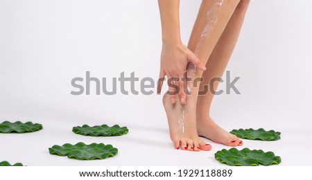 Banner- long format. Perfect smooth female feet. The hand of the elegant girl touches her legs, massage the cream on the foot . Spa, scrub and foot care concept. Water lily flowers and bodycare