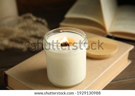 Beautiful candle with wooden wick on book Royalty-Free Stock Photo #1929130988