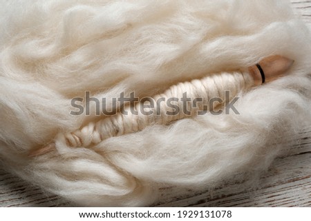 Soft white wool and spindle on wooden table, closeup Royalty-Free Stock Photo #1929131078