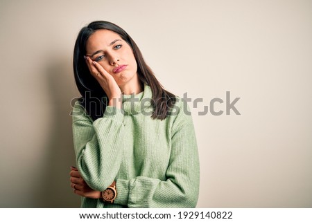 Young brunette woman with blue eyes wearing turtleneck sweater over white background thinking looking tired and bored with depression problems with crossed arms.