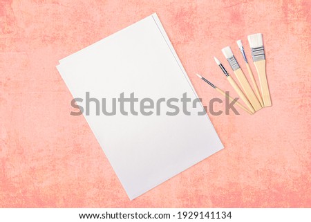 A clean white sheet and brushes on a textured pink background with space to copy.