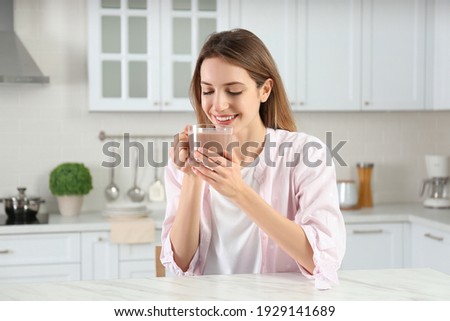 Young woman drinking chocolate milk in kitchen