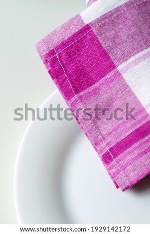 empty white dining plate and plaid pink kitchen towel close up