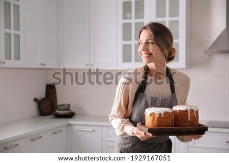 Young woman with traditional Easter cakes in kitchen, space for text
