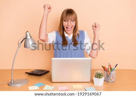 Photo portrait of woman gesturing like winner near computer in formalwear glasses isolated on pastel beige color background