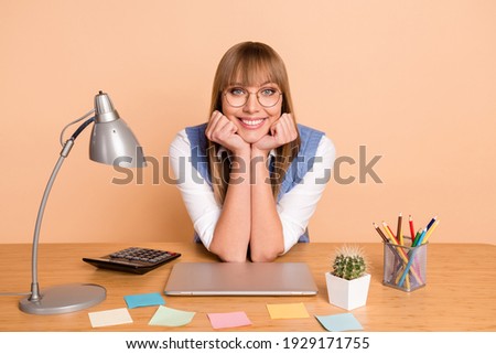 Photo portrait of woman in spectacles smiling working on desk remotely at home isolated on pastel beige color background