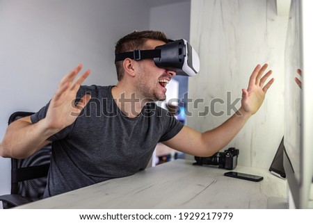 Amazing 3D stimulation, VR glasses. Young man wears virtual reality goggles and tests technology possibilities in a closed office and at home Futuristic approach model of work in the creative industry