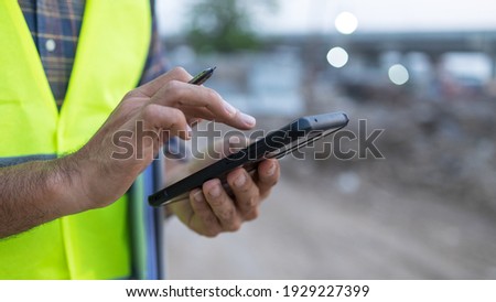 engineer working on his smartphone at the construction site Royalty-Free Stock Photo #1929227399