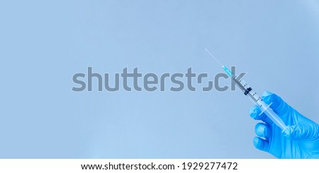 isolated on blue background: doctor's hand in glove holds a syringe vaccination against virus concept.