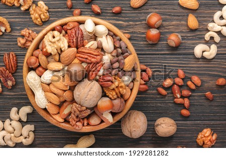 Assortment of nuts in bowls. Cashews, hazelnuts, walnuts, pistachios, pecans, pine nuts, peanuts, macadamia, almonds, brazil nuts. Food mix on wooden background, top view, copy space Royalty-Free Stock Photo #1929281282