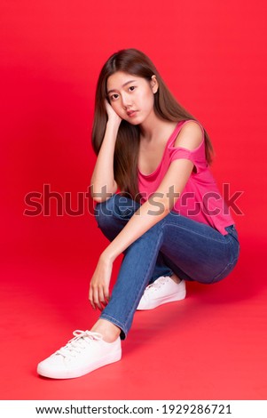 Young Asian teenage girl on red background. Casual Asian woman wearing red t-shirt. Beauty happy women smiling fresh and natural on red background. Fresh and energetic beautiful young girl smiling.