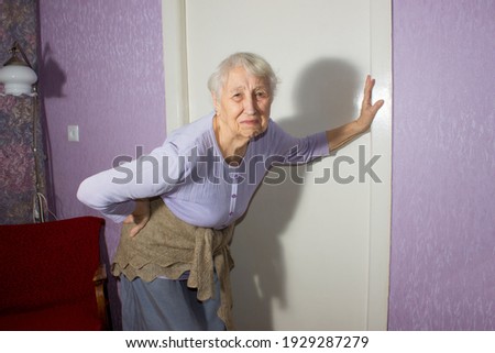 Elderly senior 75s woman with painful feelings massaging low back to reduce ache, backache discomfort. Diseases of older people, sciatic nerve injury concept Royalty-Free Stock Photo #1929287279