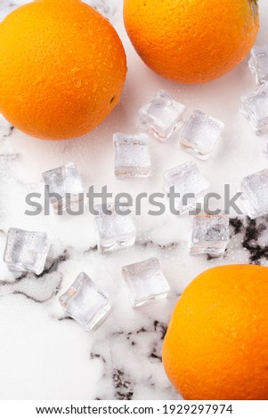Aerial view of three oranges with ice, on white marble, vertically
