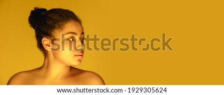 Flyer. Beautiful african-american woman's portrait isolated on yellow golden studio background in neon, monochrome. Concept of human emotions, facial expression, sales, ad, fashion and beauty.