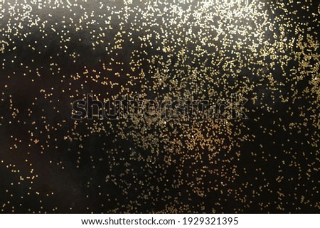 Gold (bronze) glitter shine dots confetti on black. Abstract light blink sparkle horizontal backgound.