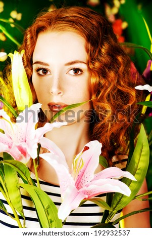 Beautiful gentle girl with red hair among the flowers.   