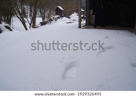 Footprints in the snow next to a shed