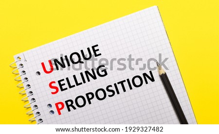 White notebook with inscription USP Unique Selling Proposition written in black pencil on a bright yellow background.