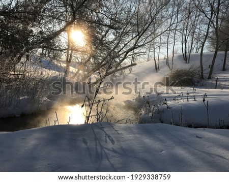 siberian forest landscape in winter with a river. the dawn is reflected in the river. shadows are reflected on the snowdrifts. steam over the water.