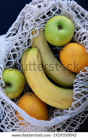 Crochet bag filled with bananas, apples and lemons. Top view.