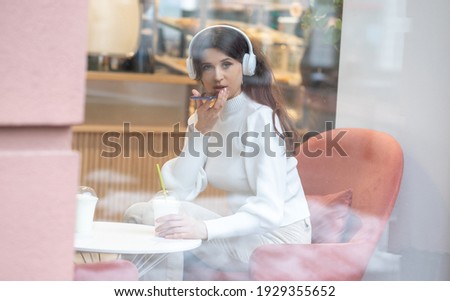 Selective focus, sharpness on eyelashes, special blur, young European woman holding a phone in her hands.
