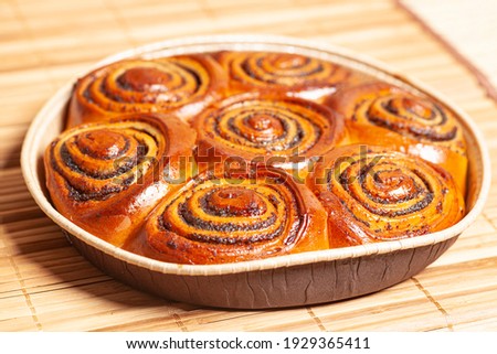 Buns with poppy seeds and cinnamon on a wooden background.