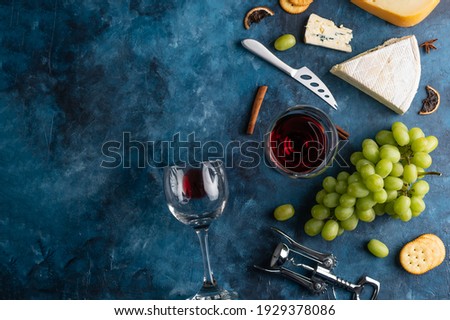 Assorted cheeses, red wine and steaks on a blue background top view