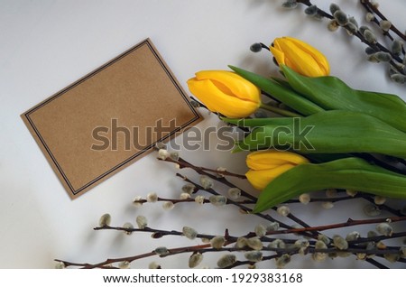 Yellow tulips and willow branches lie on the table.Spring flowers Place for text