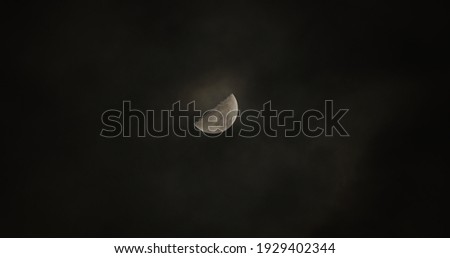 moon sickle in black sky with clouds slightly covering it so it shines through the clouds
