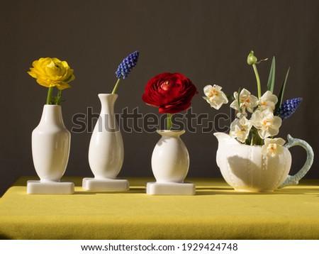 Close-up vases of different shapes and sizes with bright flowers daffodils, ranunculus, muscari are on the table