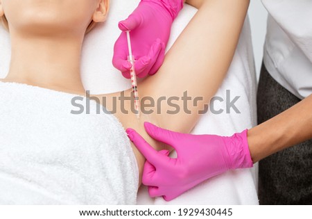 The doctor makes injections of botulinum toxin in the underarm area against hyperhidrosis. Women's cosmetology concept. Royalty-Free Stock Photo #1929430445