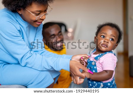 Mom and dad play with their 9 month old baby daughter on the sofa