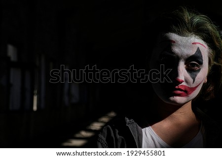 Woman portrait impersonating the Joker. Clown makeup and green hair. Joker cosplay. 