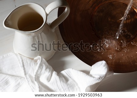 Pouring water into basin by pitcher and linen cloth Royalty-Free Stock Photo #1929503963