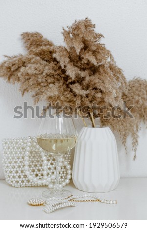 Pampas grass in white ceramic vase with glass of white wine .Still life bouquet of dried flowers. Minimal concept. Hygge, Lagom, Vintage