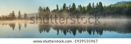 Panoramic view of forest lake in morning fog, summer travel Royalty-Free Stock Photo #1929535967