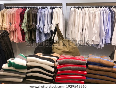 Bright colorful cotton shirts on hanger in boutique shop close up. Fashion clothes on clothing rack.with stacked colorful sweater 

