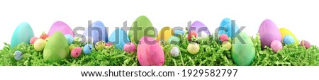 Painted Easter eggs and decorations on arranged on Easter grass. Horizontal banner isolated on white.