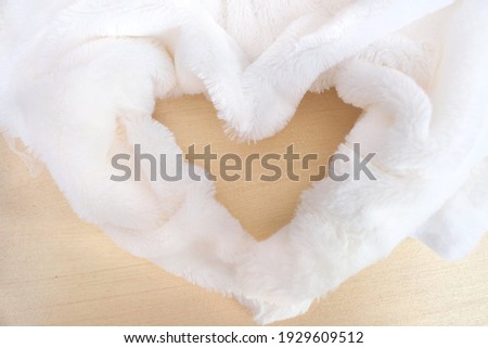 Cozy atmospheric background with white fur folded in the shape of heart. Concept of love and romance. Retro Beautiful background for Valentines Day.