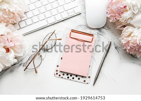 Flat lay top view women's office desk with flowers. Female workspace with laptop, flowers peonies, accessories, notebook, glasses, cup of coffee on white background. Holiday background.Copy space