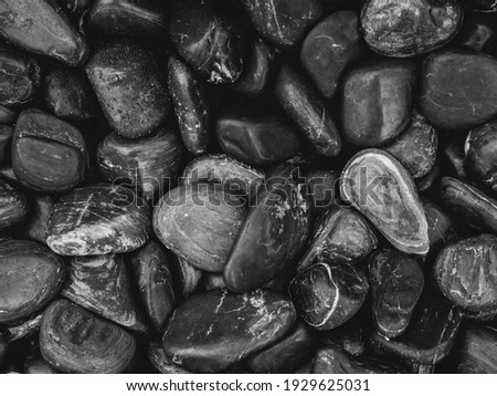 Black pebbles background texture. Close up grunge black sea stone, black and white style.